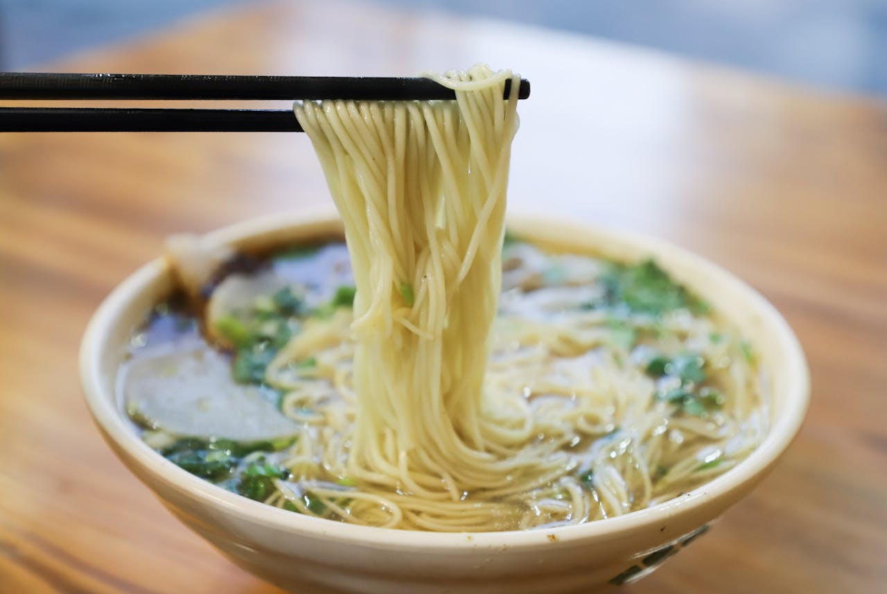 Savor the mouthwatering taste of fresh ramen noodles lifted by chopsticks.